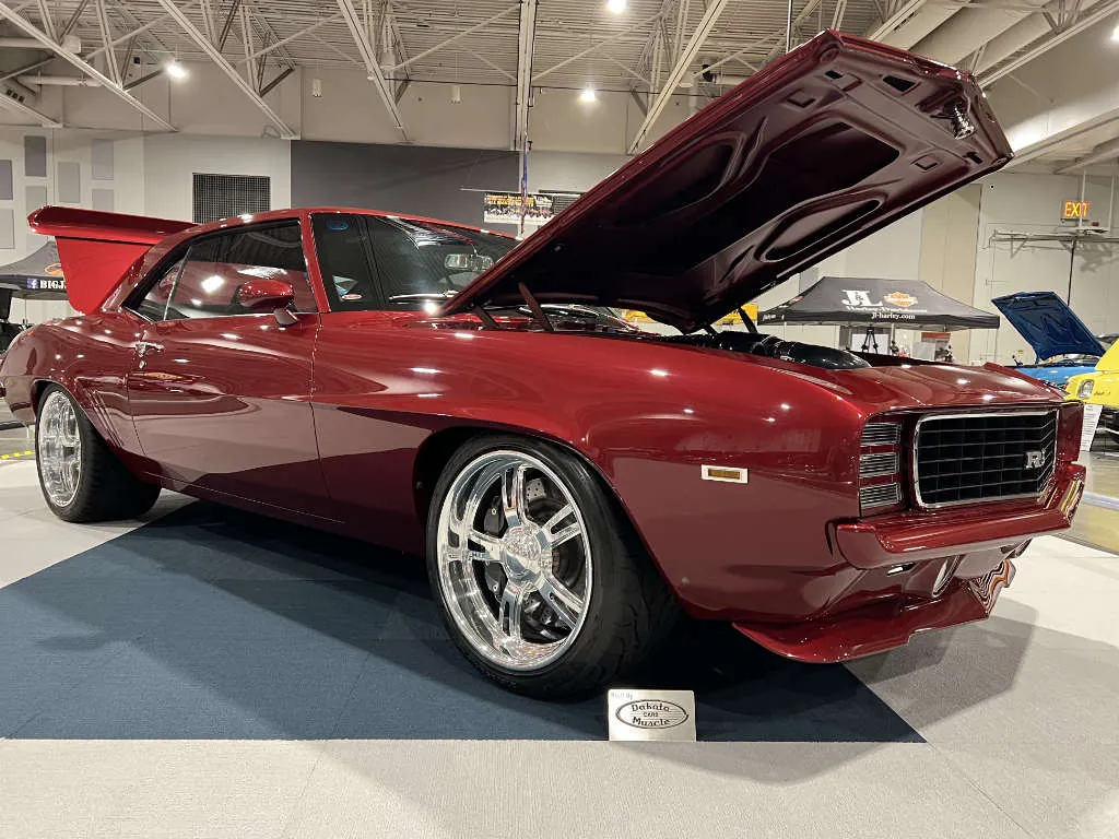 Candy red 1969 Camaro with the hood up on a show floor